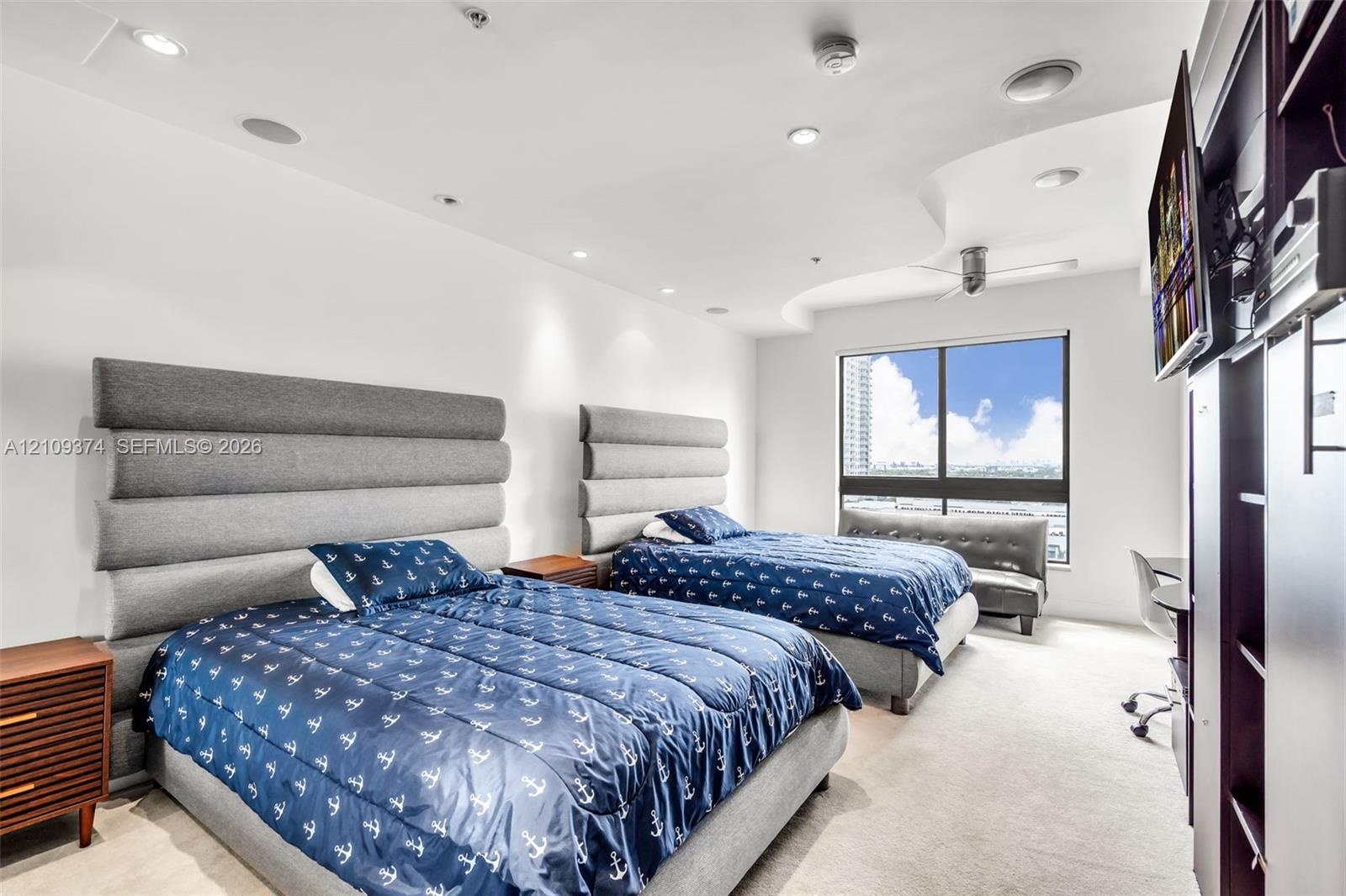 Room featuring a recessed ceiling detail, ceiling-mounted light fixtures, wall-to-wall carpeting, and a large window