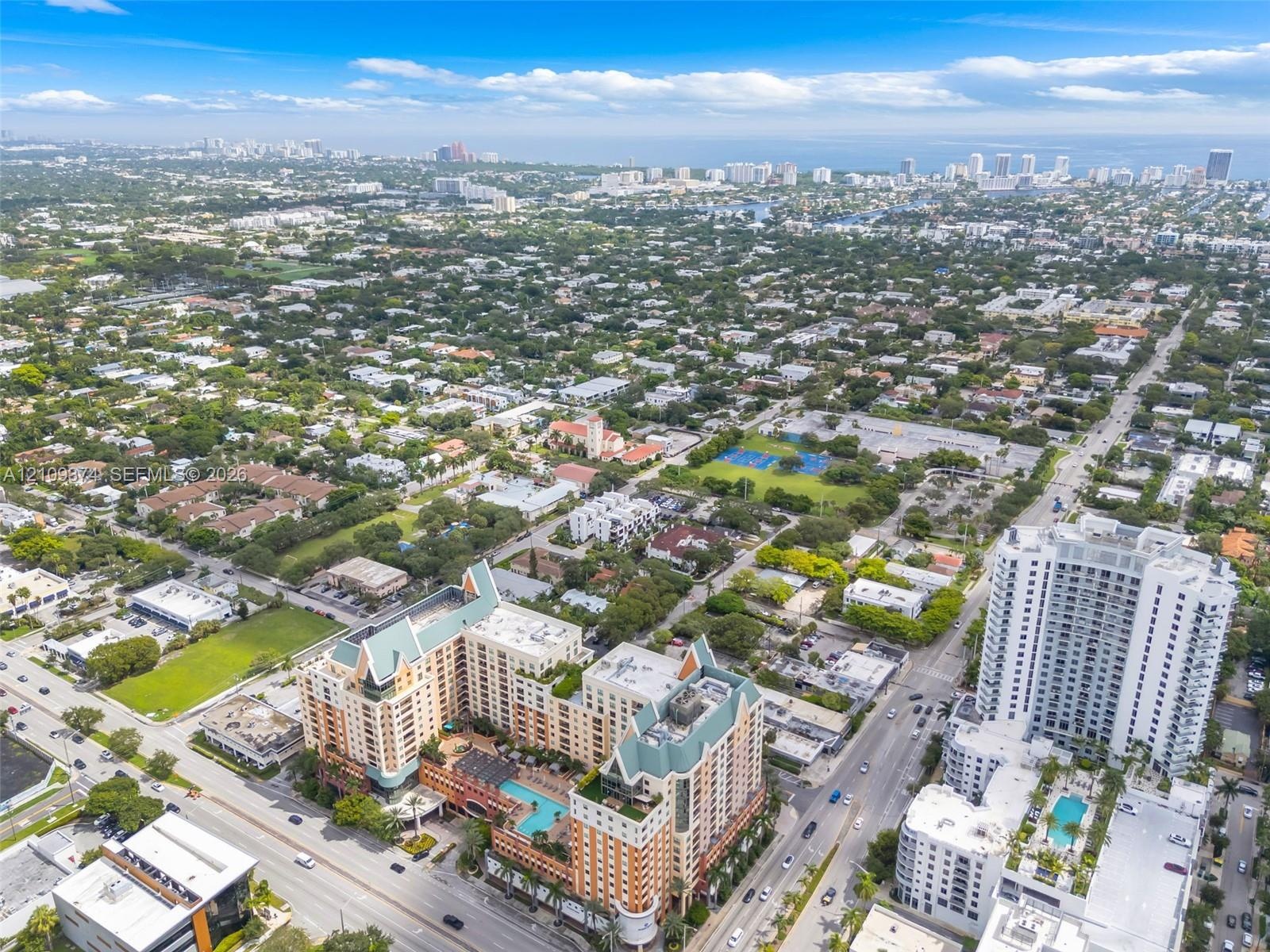 Aerial view of multi-story residential building featuring a terracotta facade, steep pitched rooflines, and an outdoor swimming pool