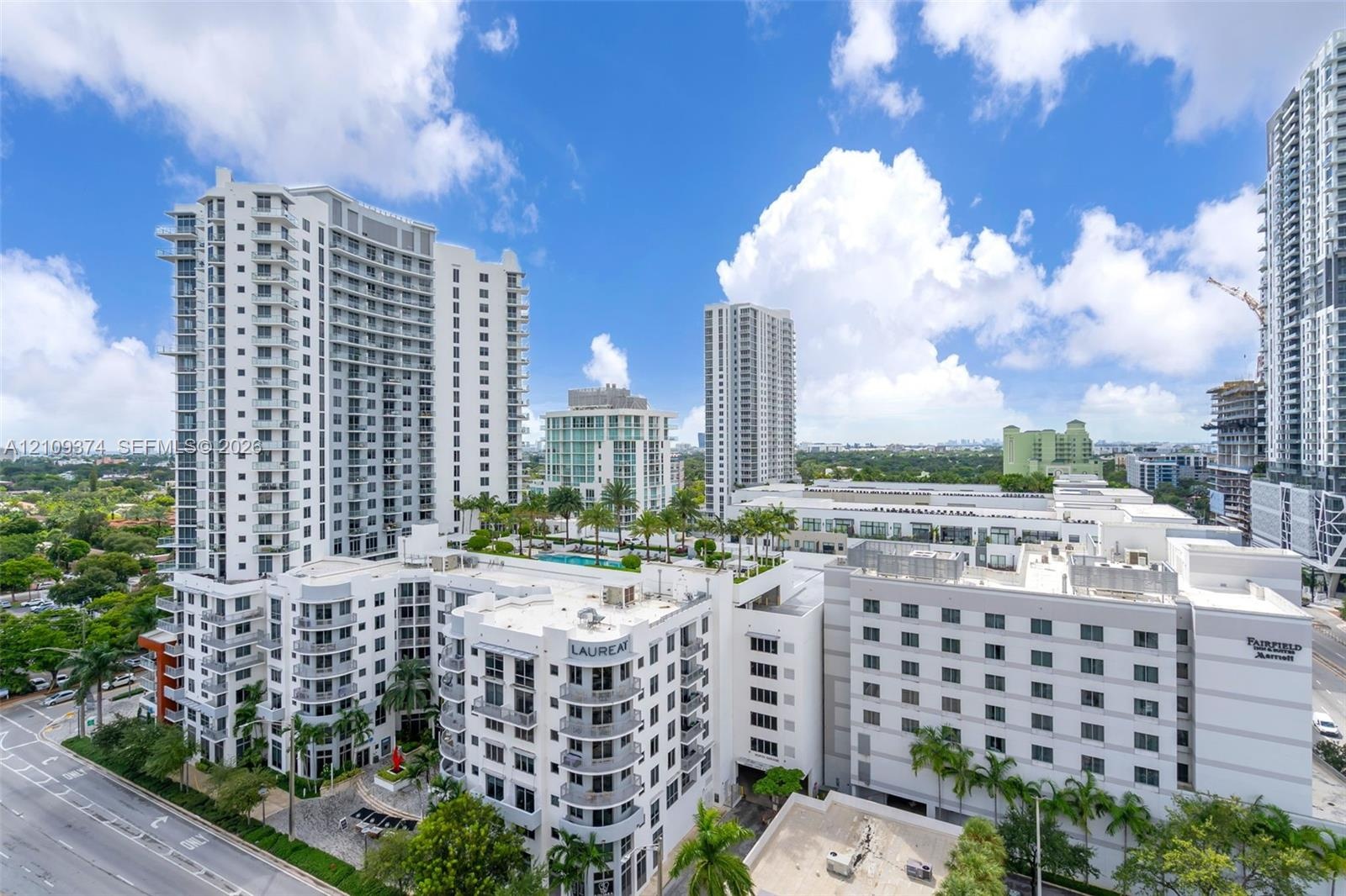 High-rise residential building featuring expansive glass balconies, a multi-level architectural design, and a rooftop terrace with a swimming pool