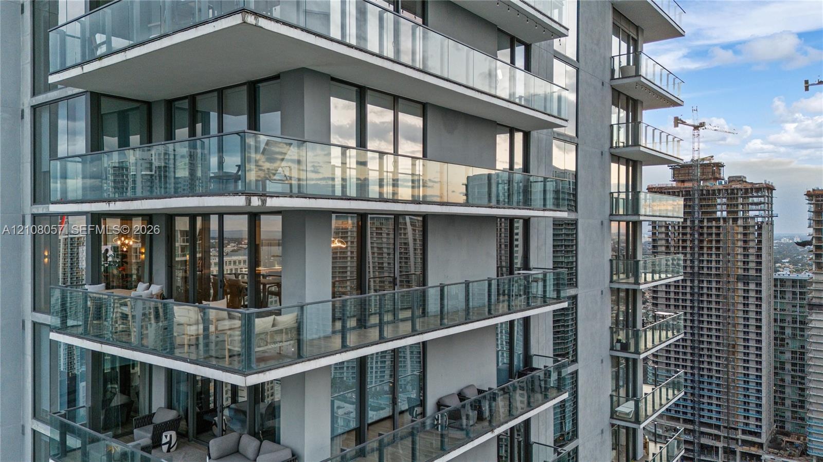 High-rise exterior featuring floor-to-ceiling glass windows and multiple cantilevered private balconies with frameless glass railings