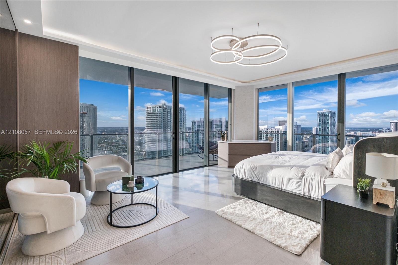 Floor-to-ceiling windows, wrap-around balcony with glass railings, large-format tile flooring, recessed cove lighting, and contemporary circular multi