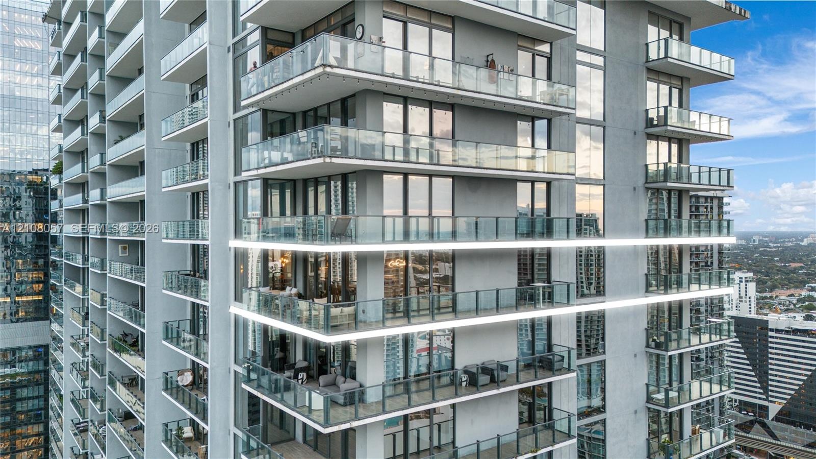 High-rise architecture featuring wrap-around glass balconies, floor-to-ceiling windows, and integrated LED exterior lighting