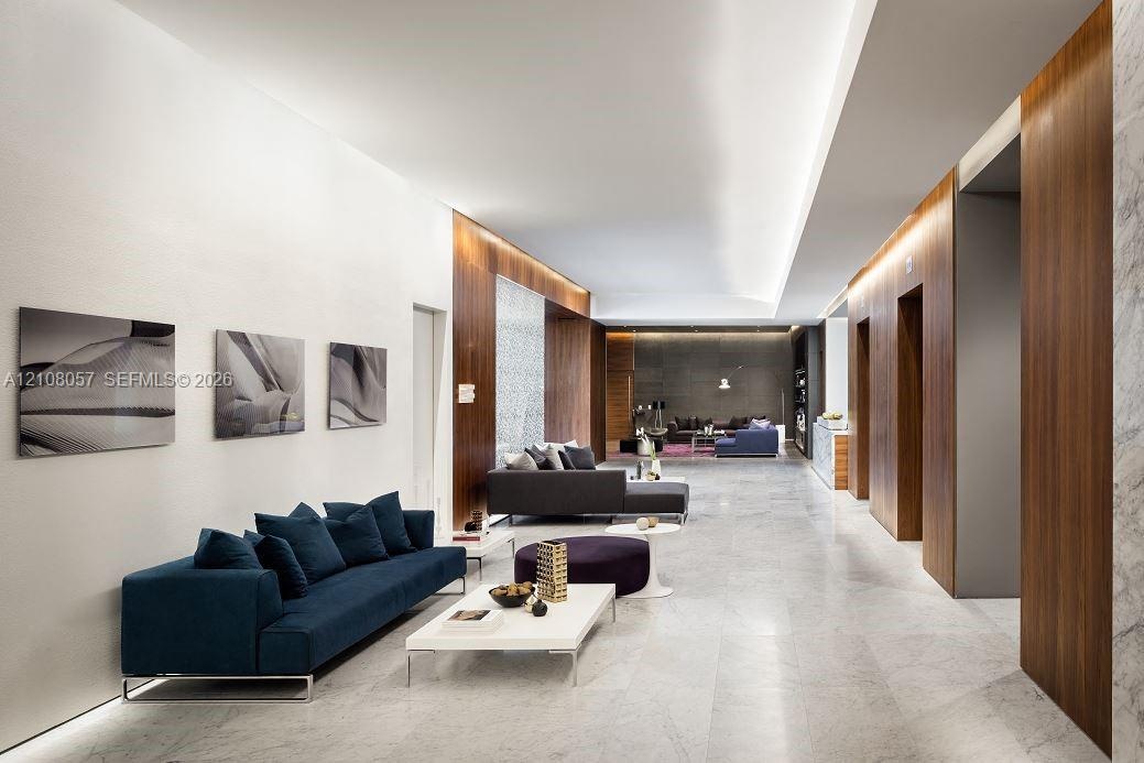 Spacious interior featuring stone flooring, wood-paneled walls, recessed ceiling lighting, and smooth-finish white walls