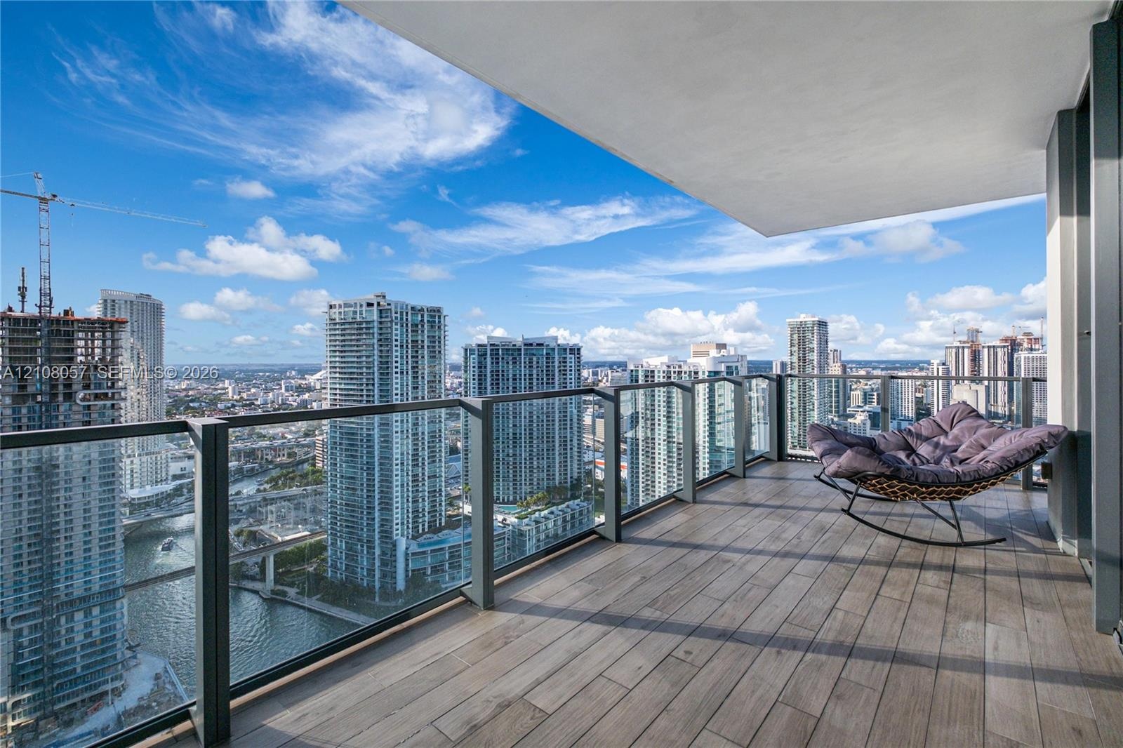 Covered balcony featuring wood-finish tile flooring and a glass-paneled railing
