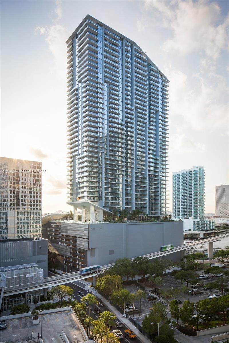 High-rise structure featuring floor-to-ceiling glass windows, wrap-around private balconies, and a multi-level concrete and glass exterior