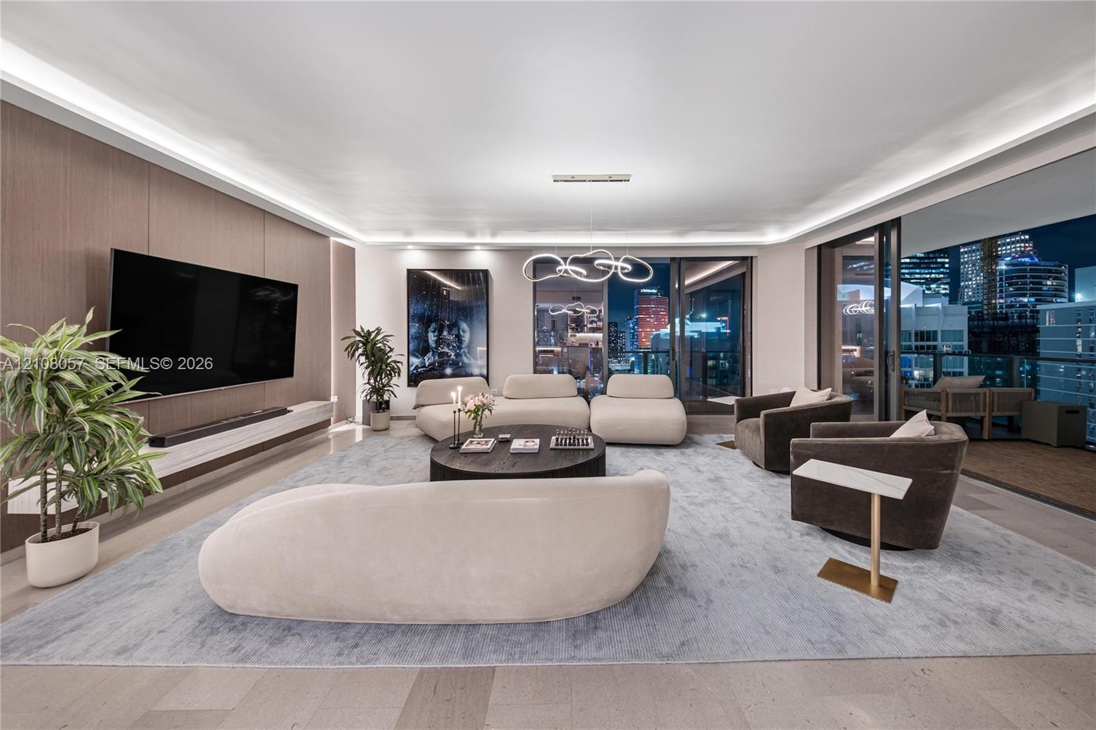 Floor-to-ceiling sliding glass doors, integrated cove lighting, wood-paneled accent wall with built-in media console, and large-format tile flooring