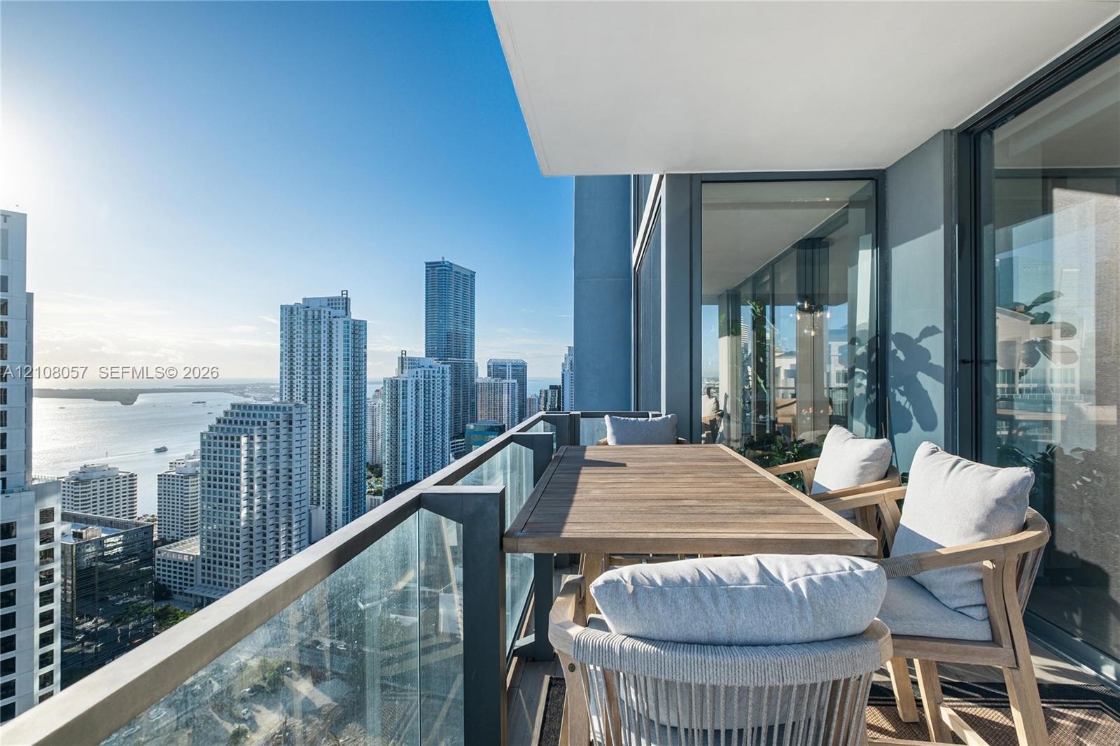 Covered balcony featuring floor-to-ceiling glass panel railings and expansive cityscape and water scenery