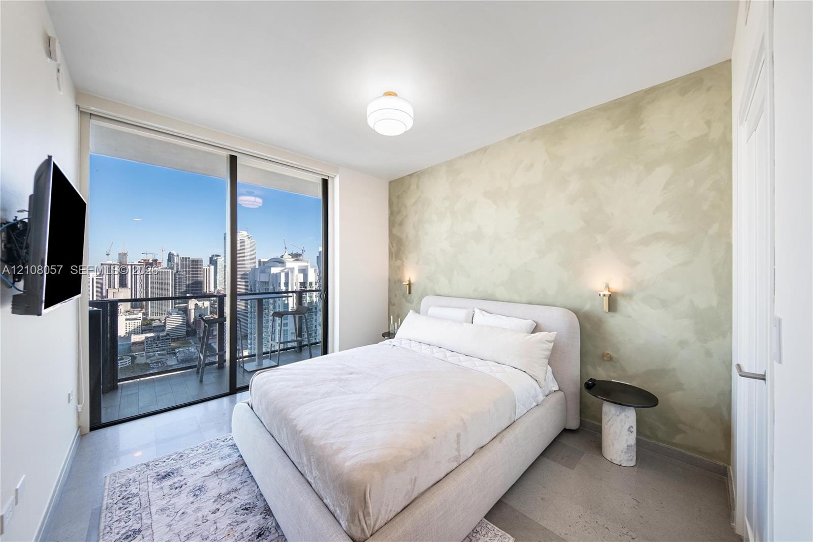 Floor-to-ceiling glass sliding doors, private balcony, polished concrete flooring, custom textured wall finish, and wall-mounted brass lighting fixtur