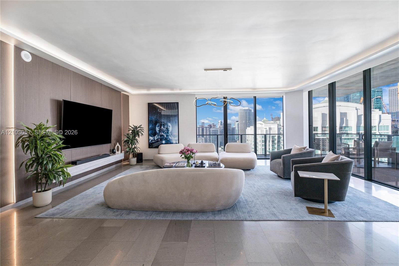 Living area featuring floor-to-ceiling windows, wood-paneled accent wall, recessed perimeter lighting, custom floating media console, and large-format