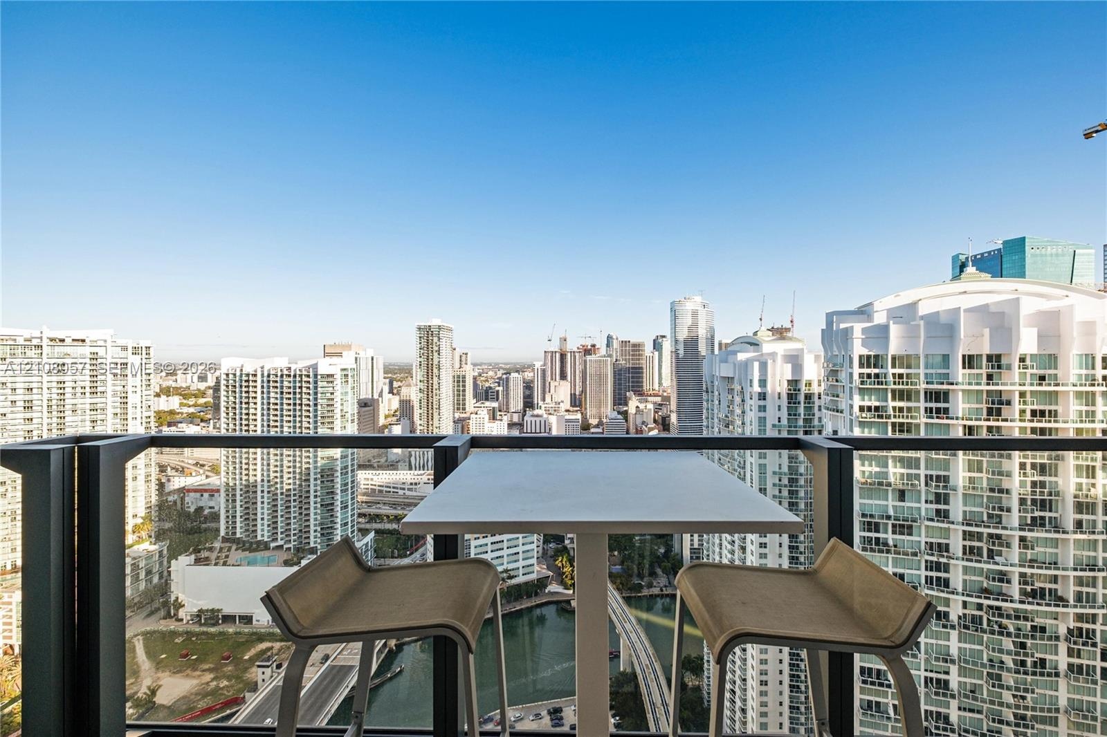Private balcony featuring a black metal railing, overlooking an expansive metropolitan skyline and river