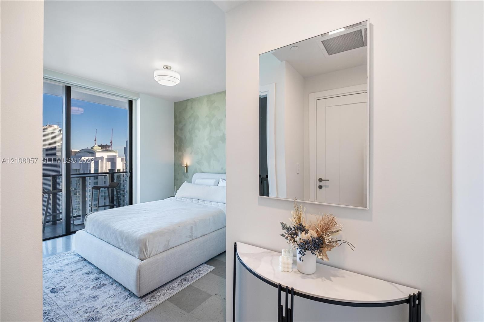 Floor-to-ceiling windows, private balcony, wall-mounted light fixture, textured accent wall, and stone-finish flooring