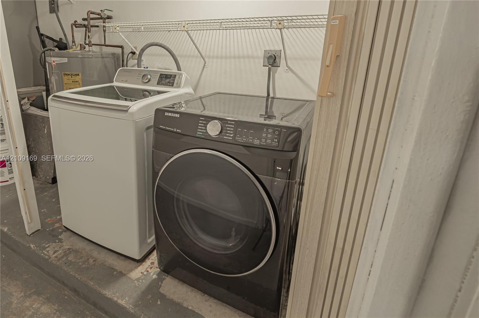 Laundry area equipped with a top-load washer, front-load dryer, and wall-mounted wire shelving