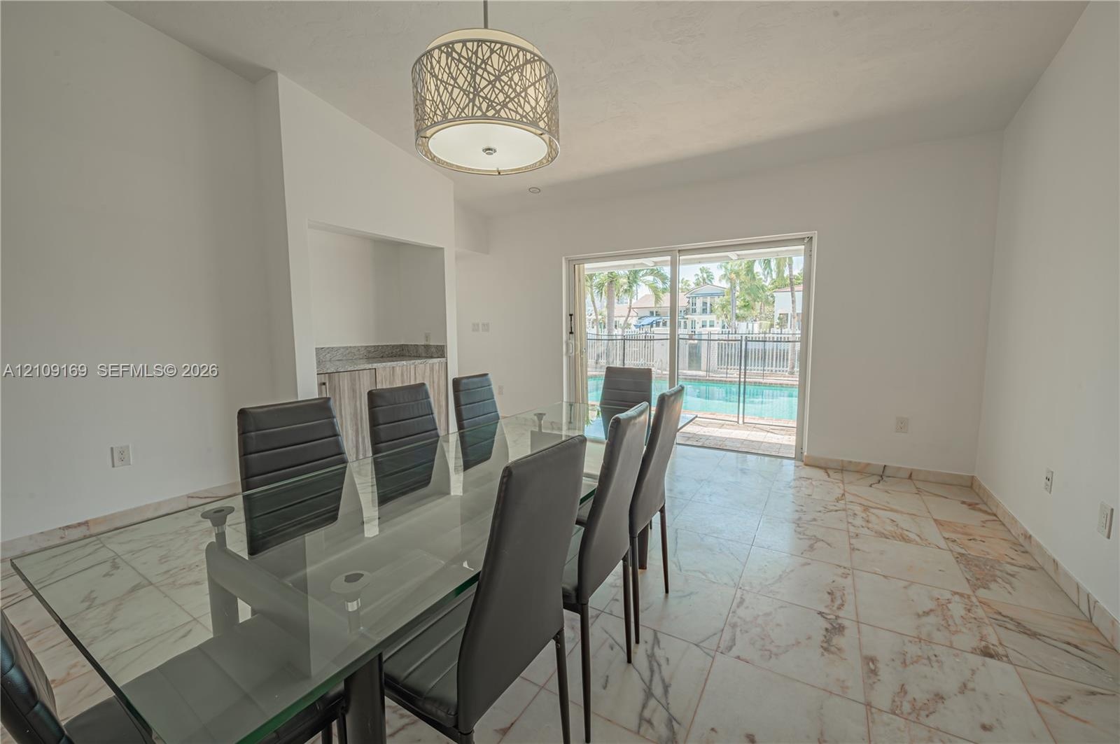 Dining area featuring stone-finish flooring, a cylindrical pendant light, built-in recessed cabinetry, and sliding glass doors
