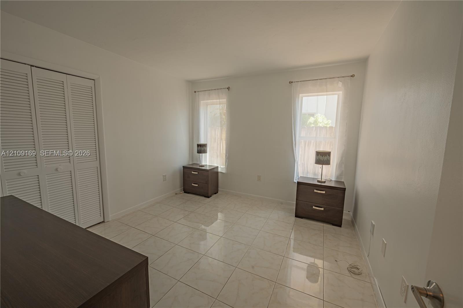 Interior space featuring large-format ceramic tile flooring, neutral walls, and a built-in closet with louvered double doors