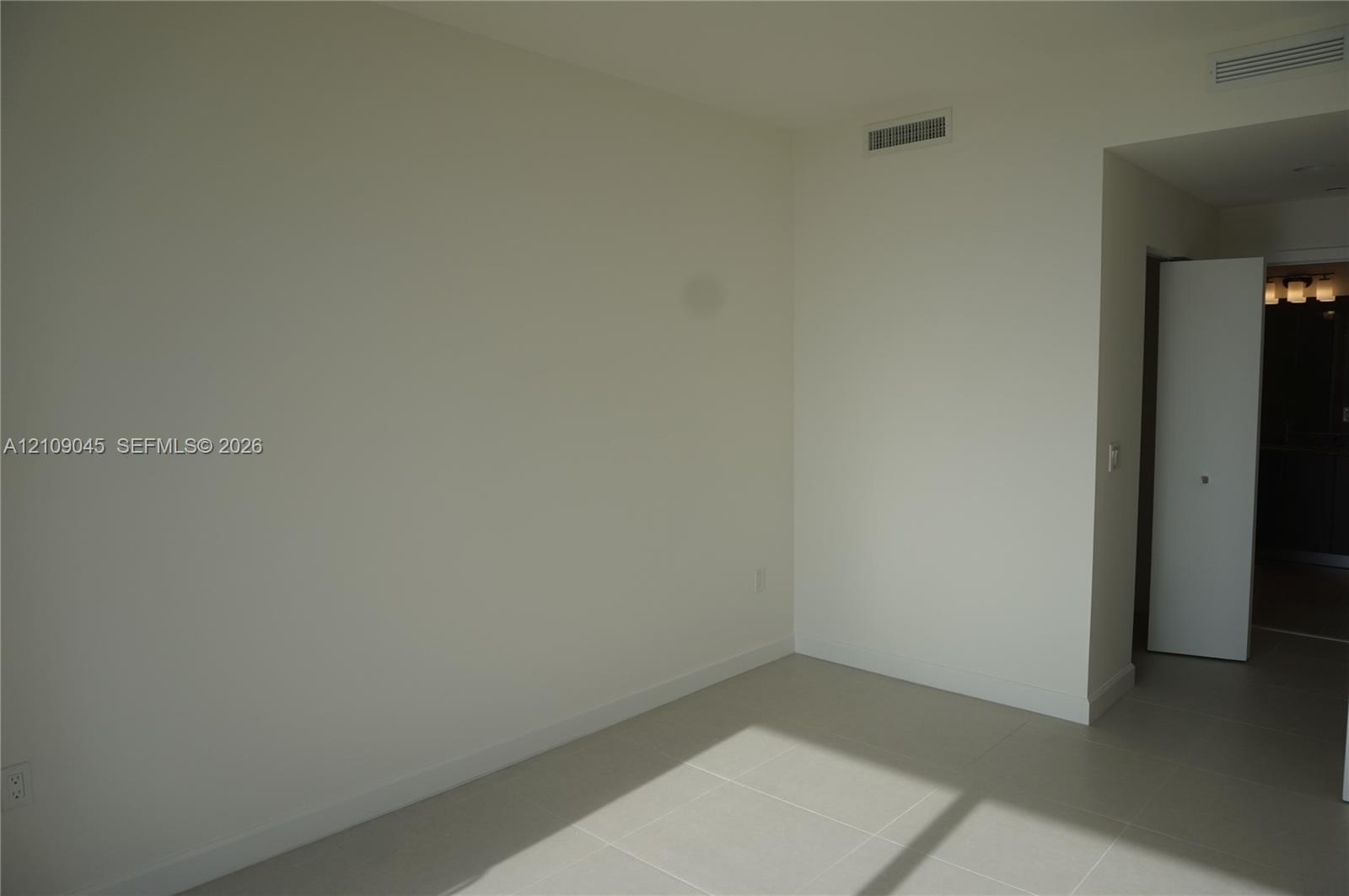 Neutral-toned interior space featuring light-colored tile flooring and white wall finishes