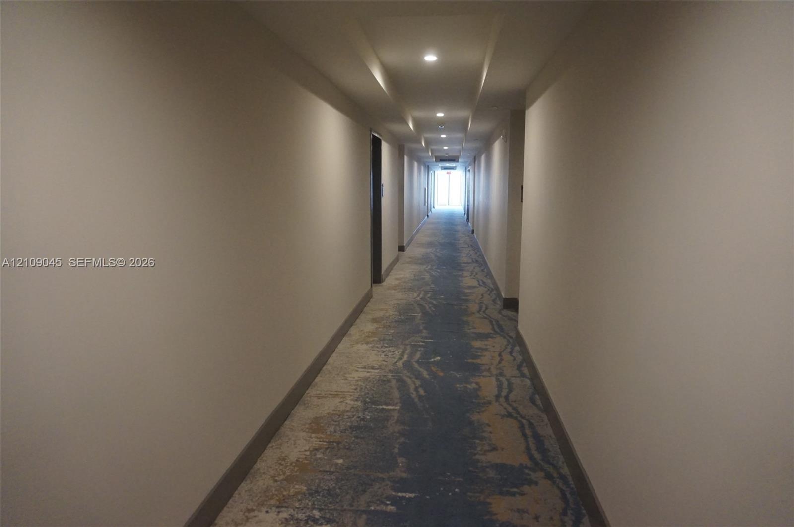 Hallway featuring patterned carpet flooring, recessed ceiling lighting, and neutral-toned walls
