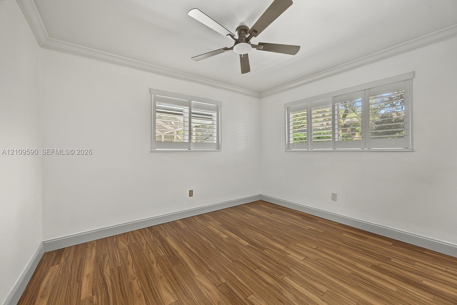 Bedroom - 4 Wood-finish flooring, plantation shutters, crown molding, and a central ceiling fan