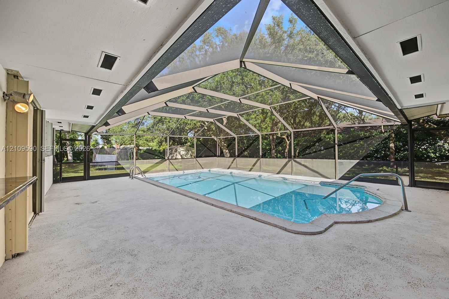 Screened-in pool enclosure featuring a covered patio, recessed lighting, and integrated pool entry railing