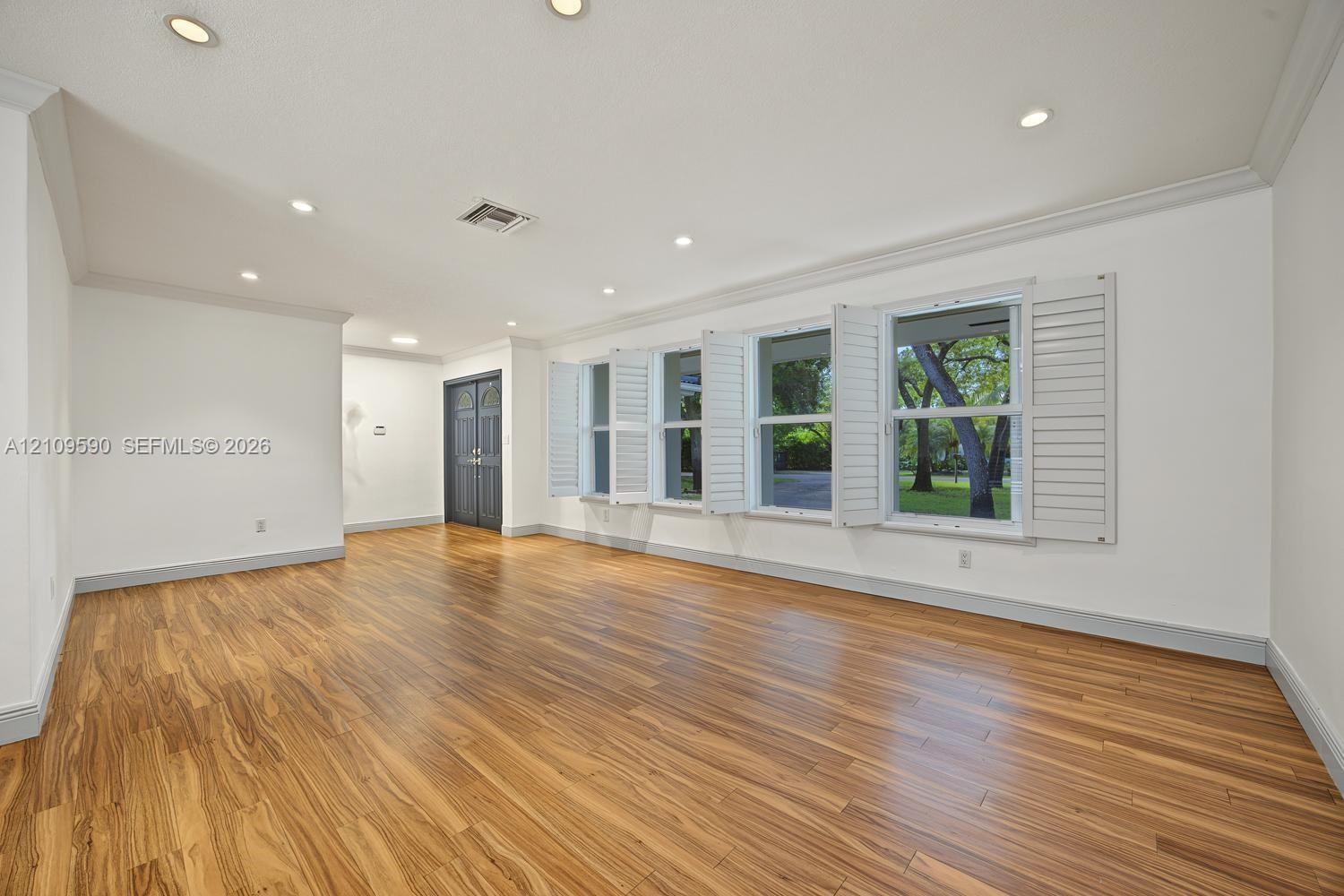 Open-concept interior featuring wood-finish flooring, recessed lighting, crown molding, and plantation shutters
