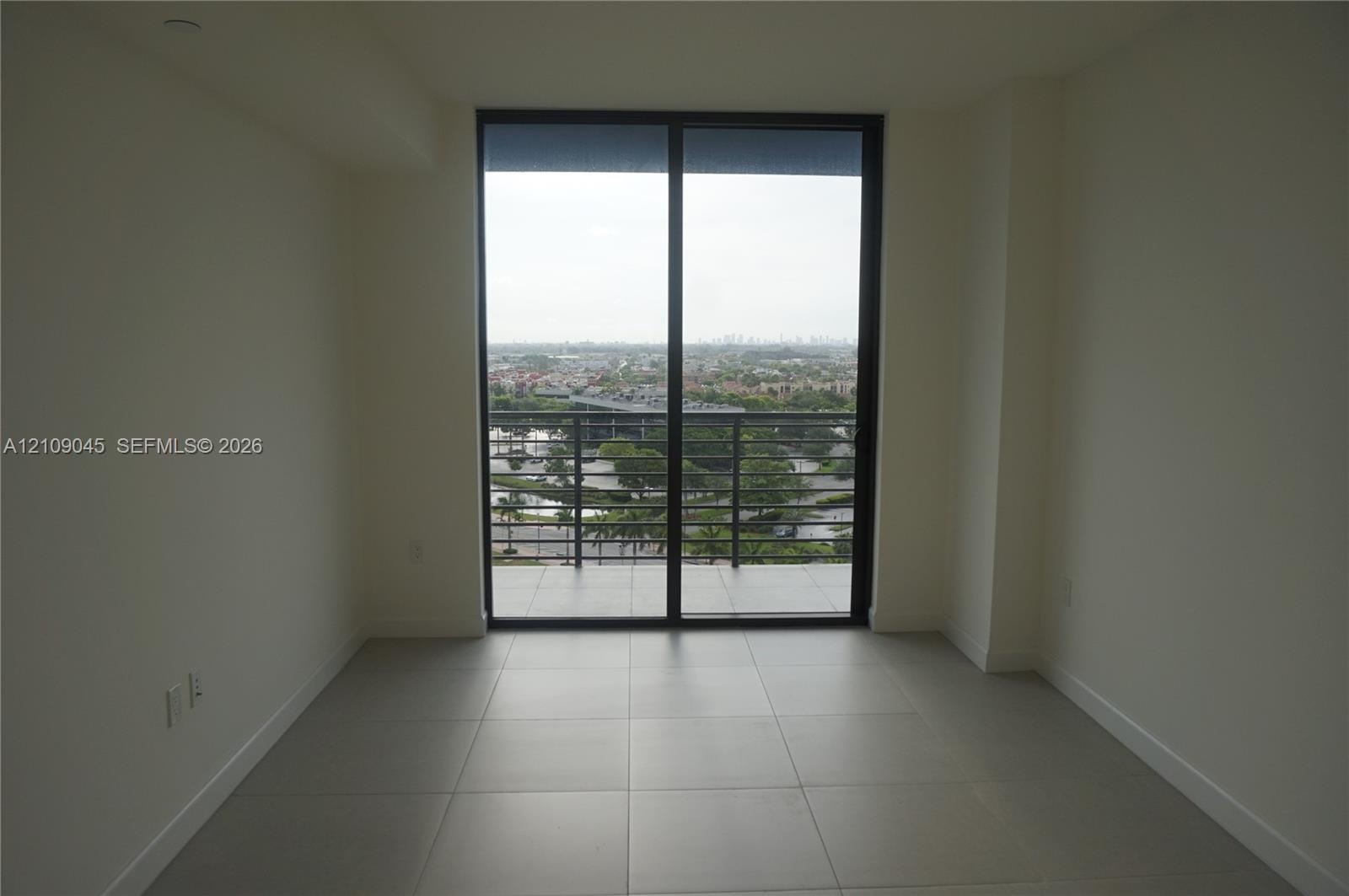 Large-format tile flooring, black-framed sliding glass doors, and a private balcony featuring metal railings and exterior tile flooring