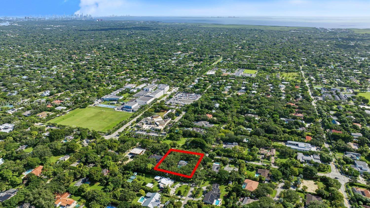 Aerial perspective of a sprawling property featuring dense mature tree canopy and expansive grounds situated within a verdant residential setting
