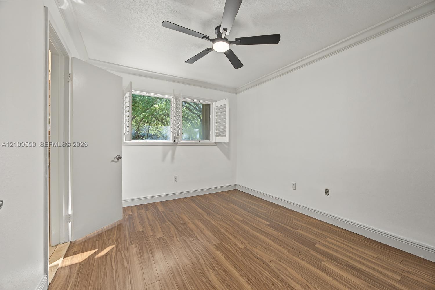 Bedroom 2 - Room featuring wood-finish flooring, crown molding, a ceiling fan with integrated lighting, and operable louvered window shutters