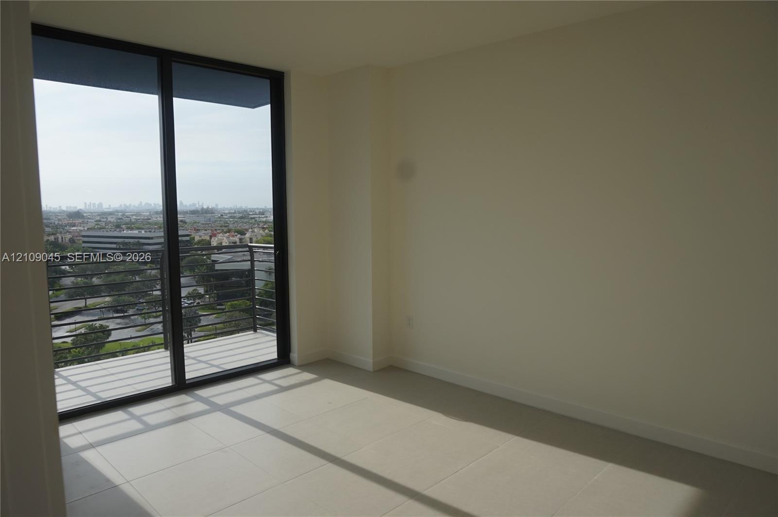 Floor-to-ceiling sliding glass doors, private balcony with metal railing, and neutral tile flooring