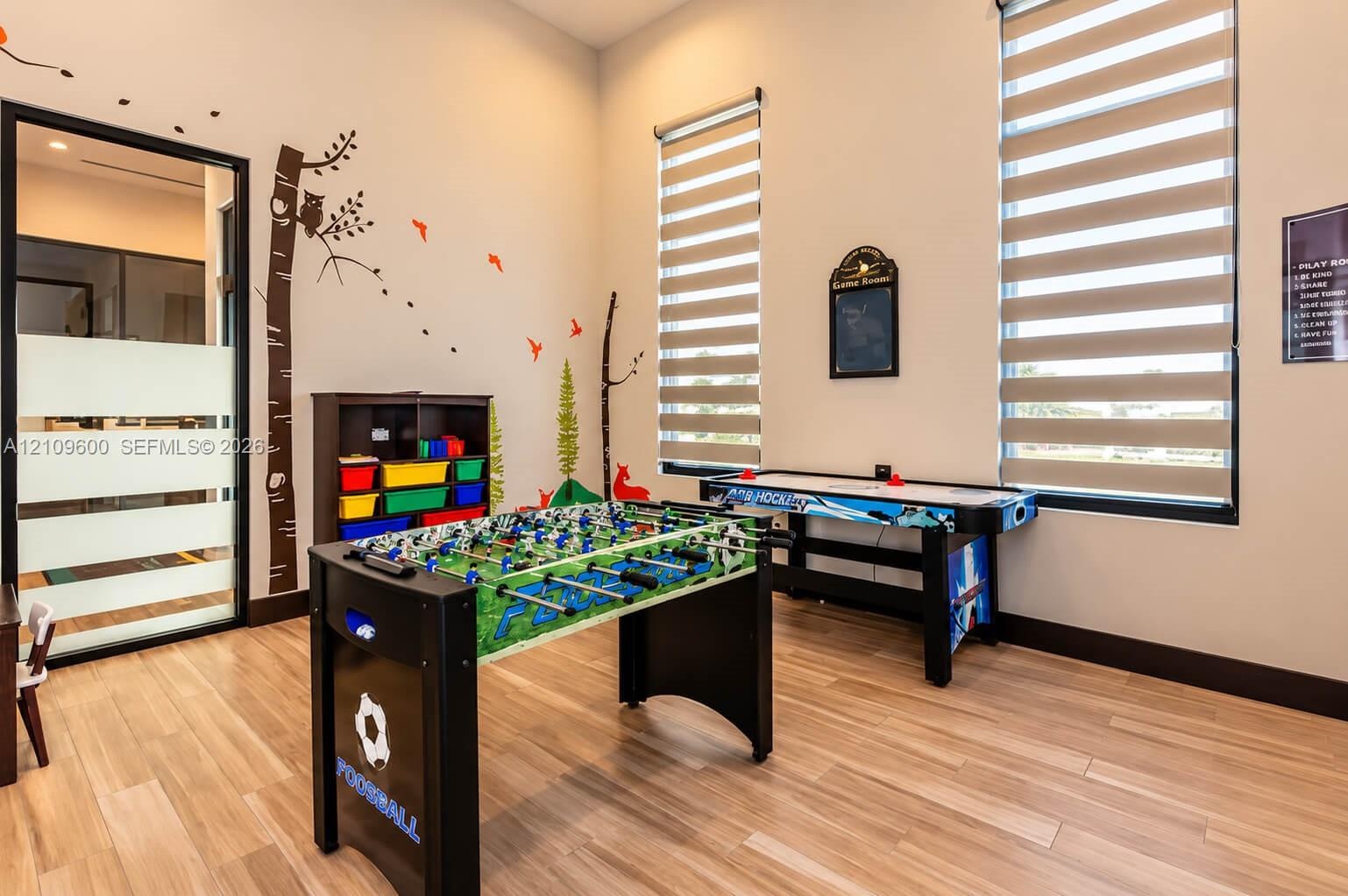 Room with wood-finish flooring, high ceilings, dual windows with integrated blinds, and a glass-paneled door