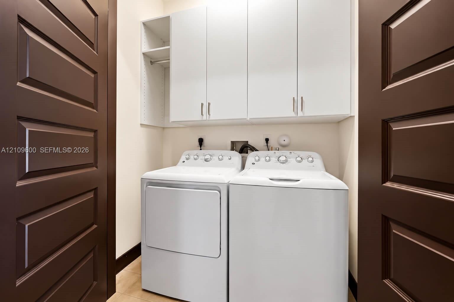 Laundry area featuring white built-in cabinetry, open shelving, and dark-toned paneled doors