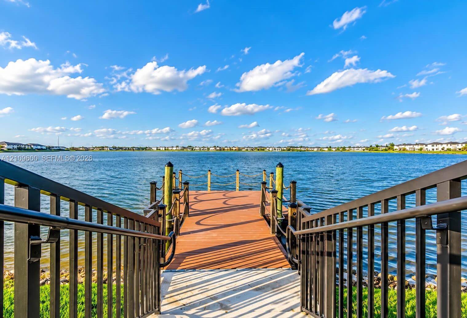 Private dock featuring composite decking, vertical wood pilings, and black metal railings with nautical rope accents