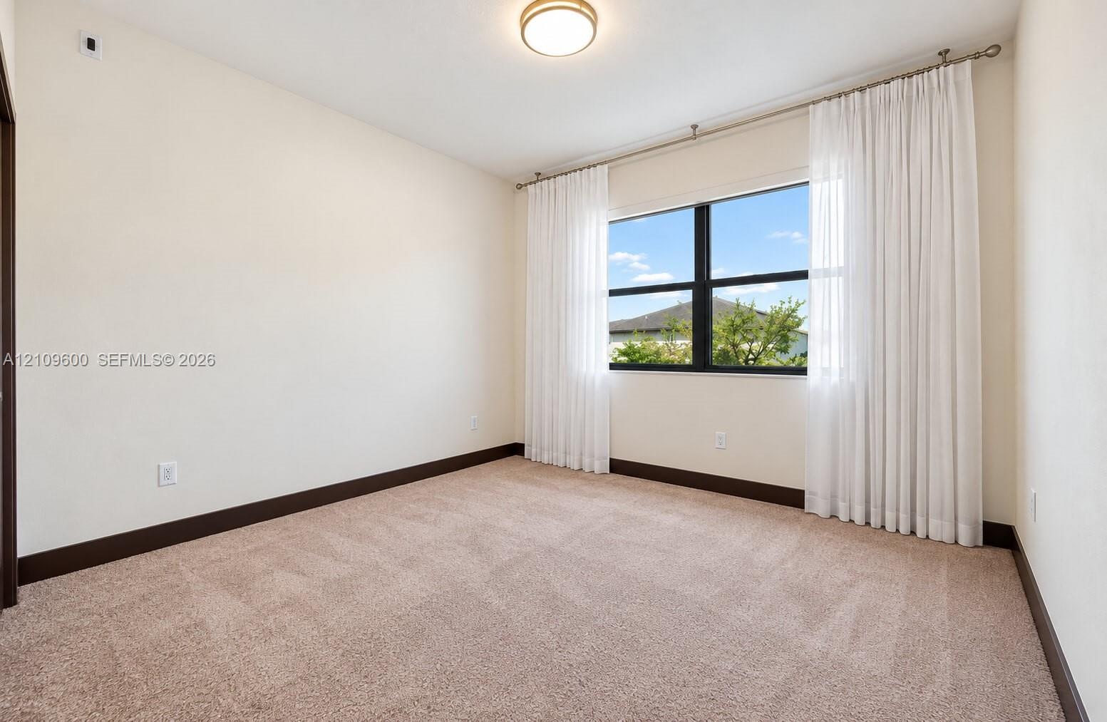Neutral-toned interior room featuring wall-to-wall carpeting, high-contrast dark trim, and a multi-pane window with dark framing