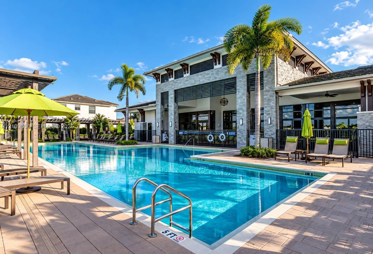 Swimming pool with stone-clad exterior building, covered pavilion, paver decking, and metal fencing