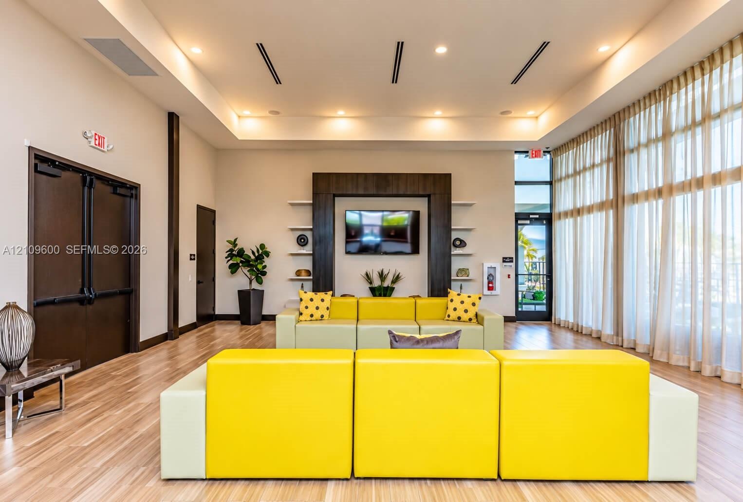 Common area featuring a tray ceiling, recessed lighting, wood-finish flooring, floor-to-ceiling windows, and built-in shelving