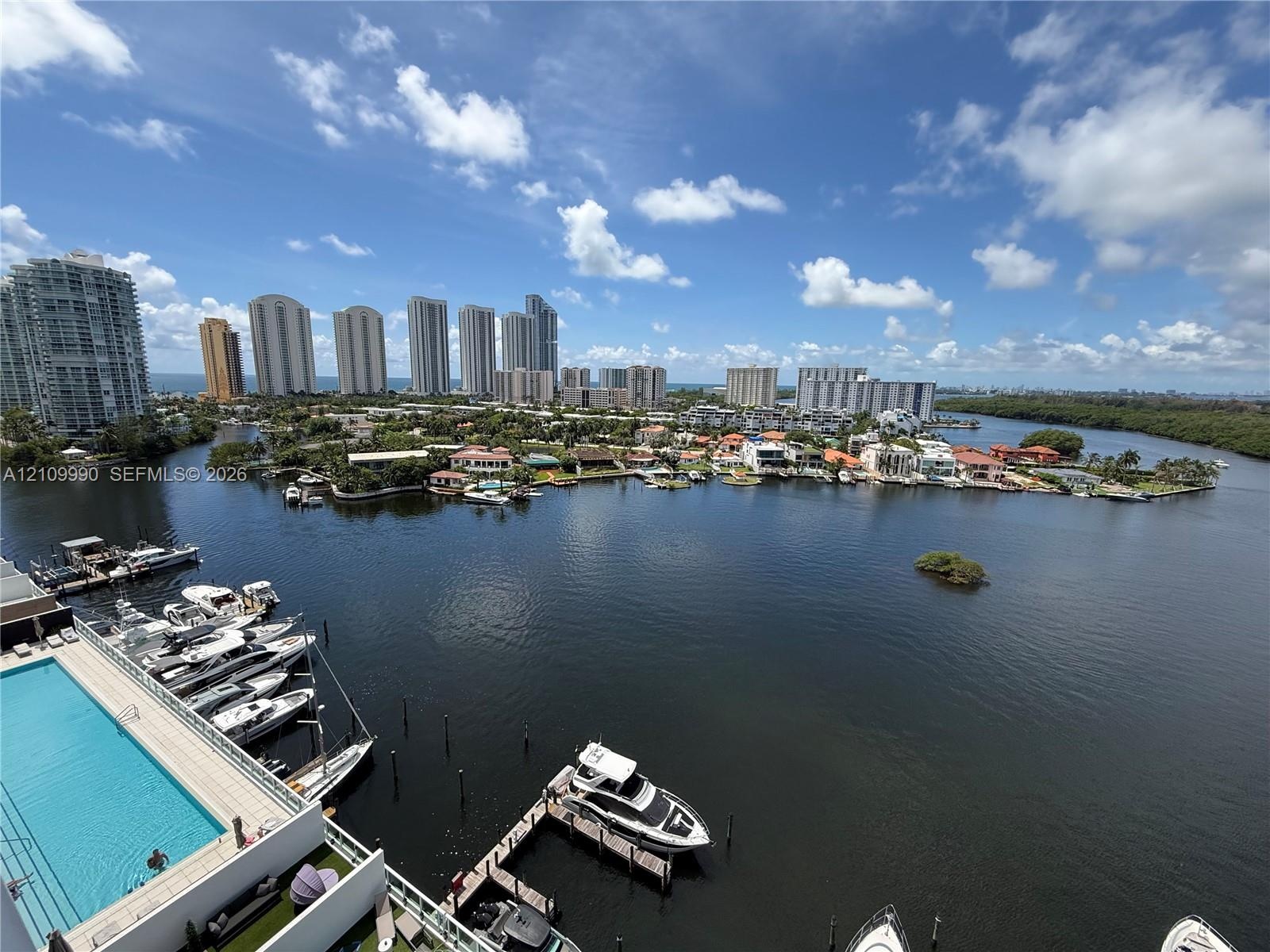 Waterfront high-rise balcony featuring a rectangular swimming pool, private boat slips, and panoramic coastal and skyline scenery