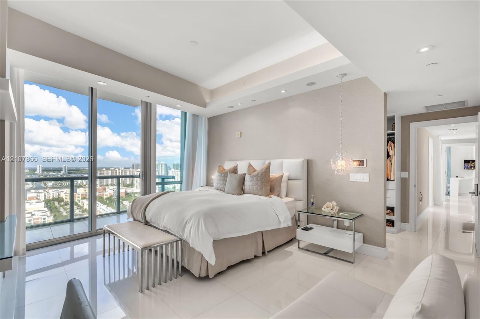 Floor-to-ceiling glass sliding doors, tray ceilings with recessed lighting, polished porcelain tile flooring, textured wall finishes, and a dedicated 
