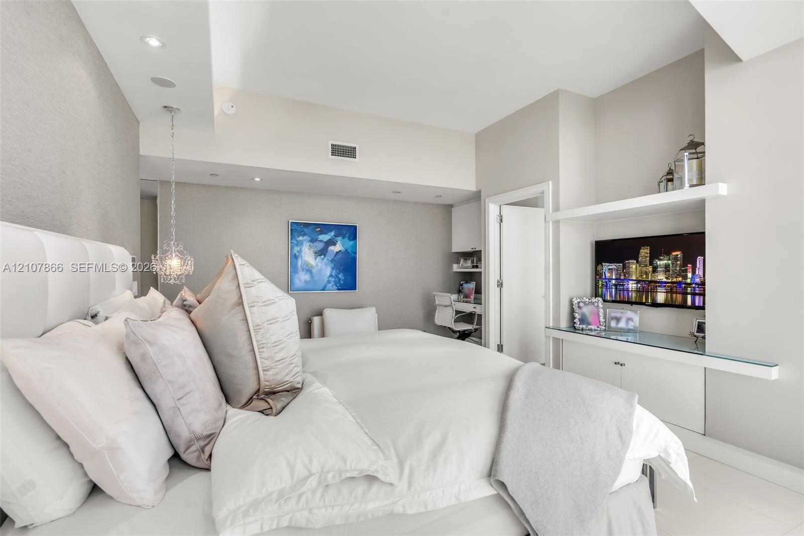 Built-in media console with glass shelving, integrated desk area, recessed lighting, and decorative pendant fixture