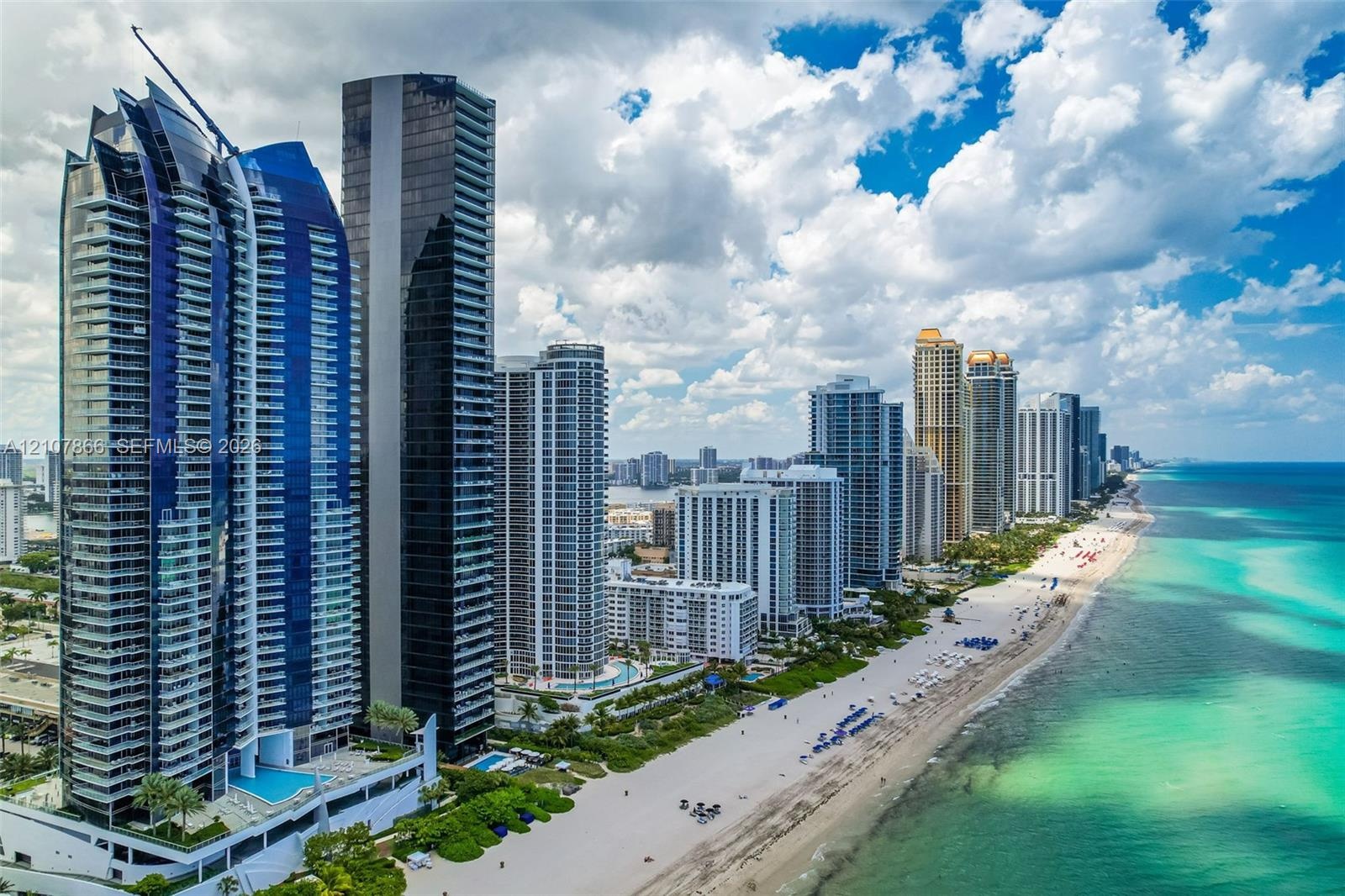 High-rise architecture featuring blue-tinted glass curtain walls and wrap-around balconies, situated directly on the Atlantic coastline with immediate