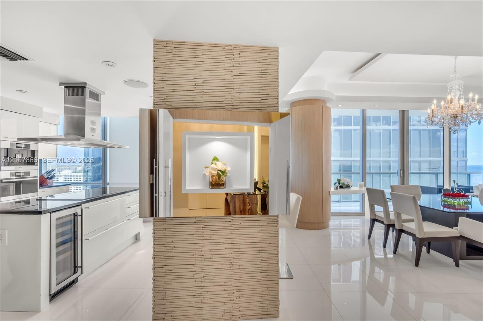 Stacked stone accent wall with a recessed display niche, white high-gloss cabinetry, stainless steel range hood, built-in wine refrigerator, and floor