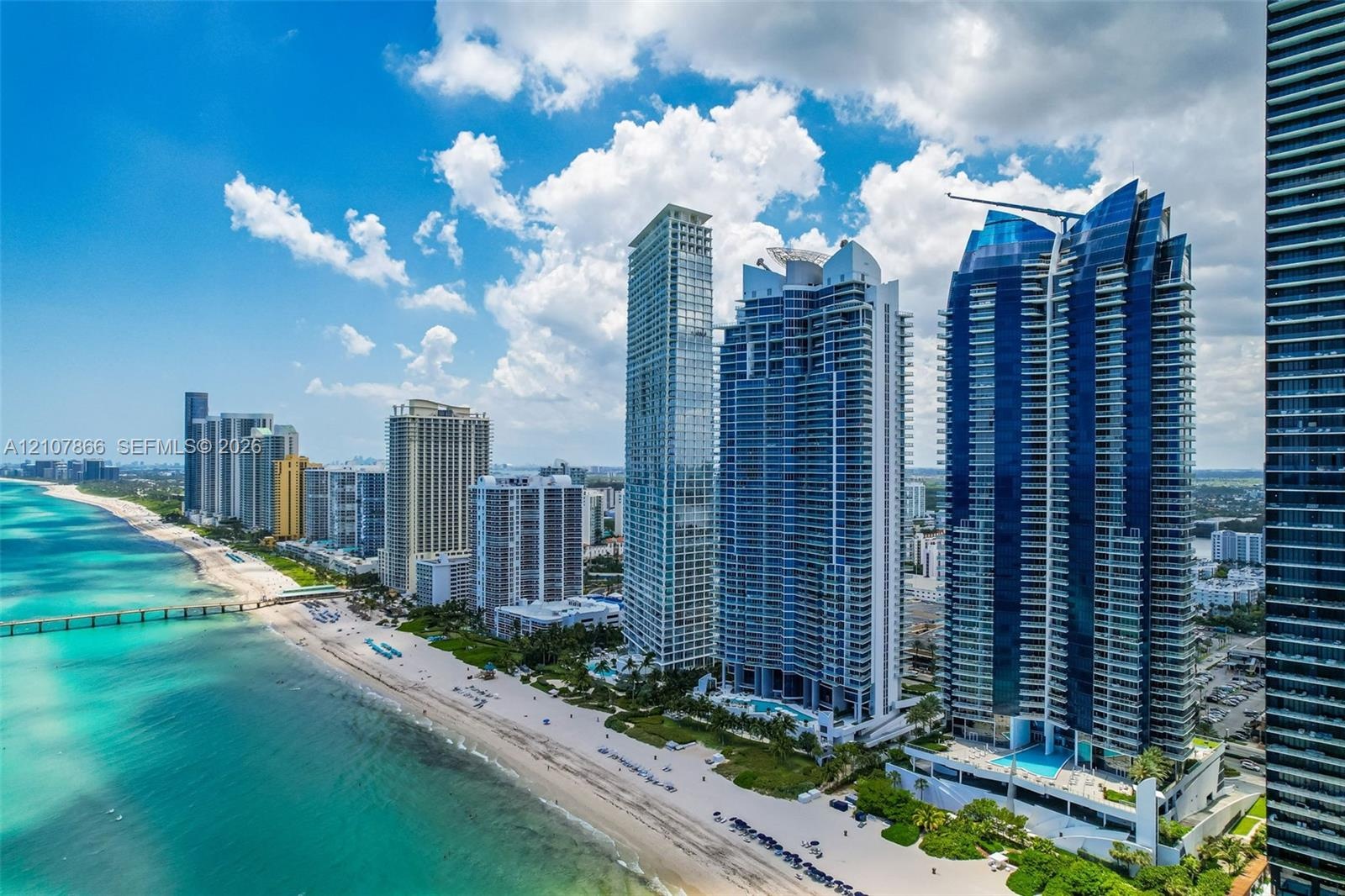 Coastal high-rise buildings featuring floor-to-ceiling glass facades, prominent balconies, and direct oceanfront positioning