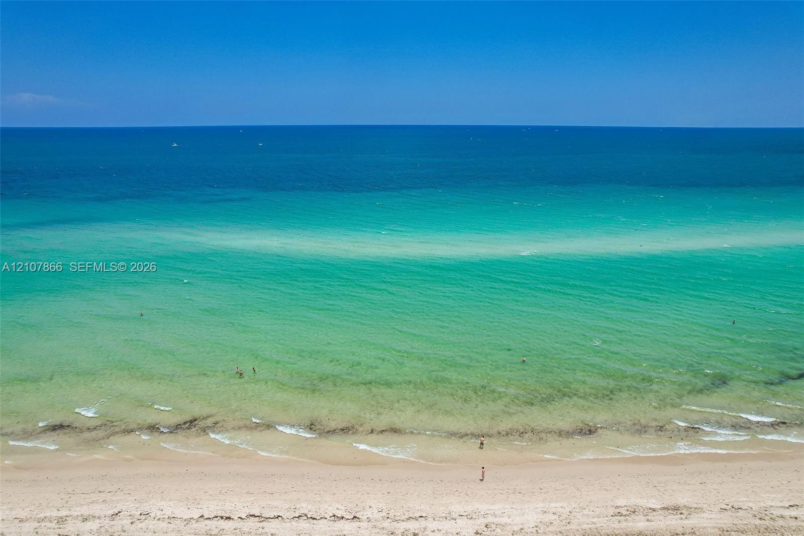 Direct oceanfront access featuring a sandy beach, clear turquoise water, and an expansive horizon