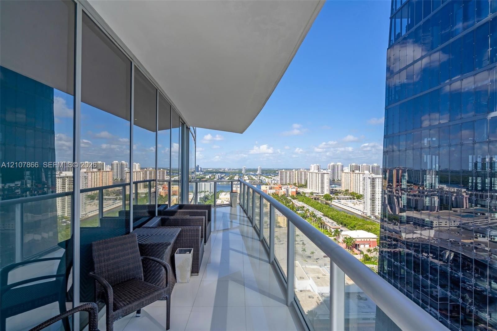 Covered balcony with floor-to-ceiling glass paneling and a metal railing