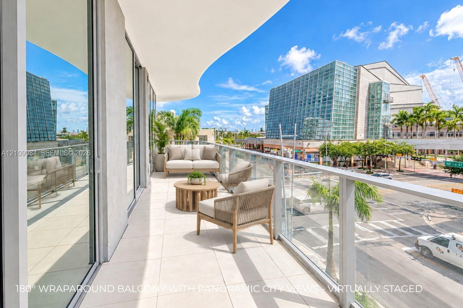Expansive curved balcony with large-format floor tile, glass panel railing, and floor-to-ceiling sliding glass doors