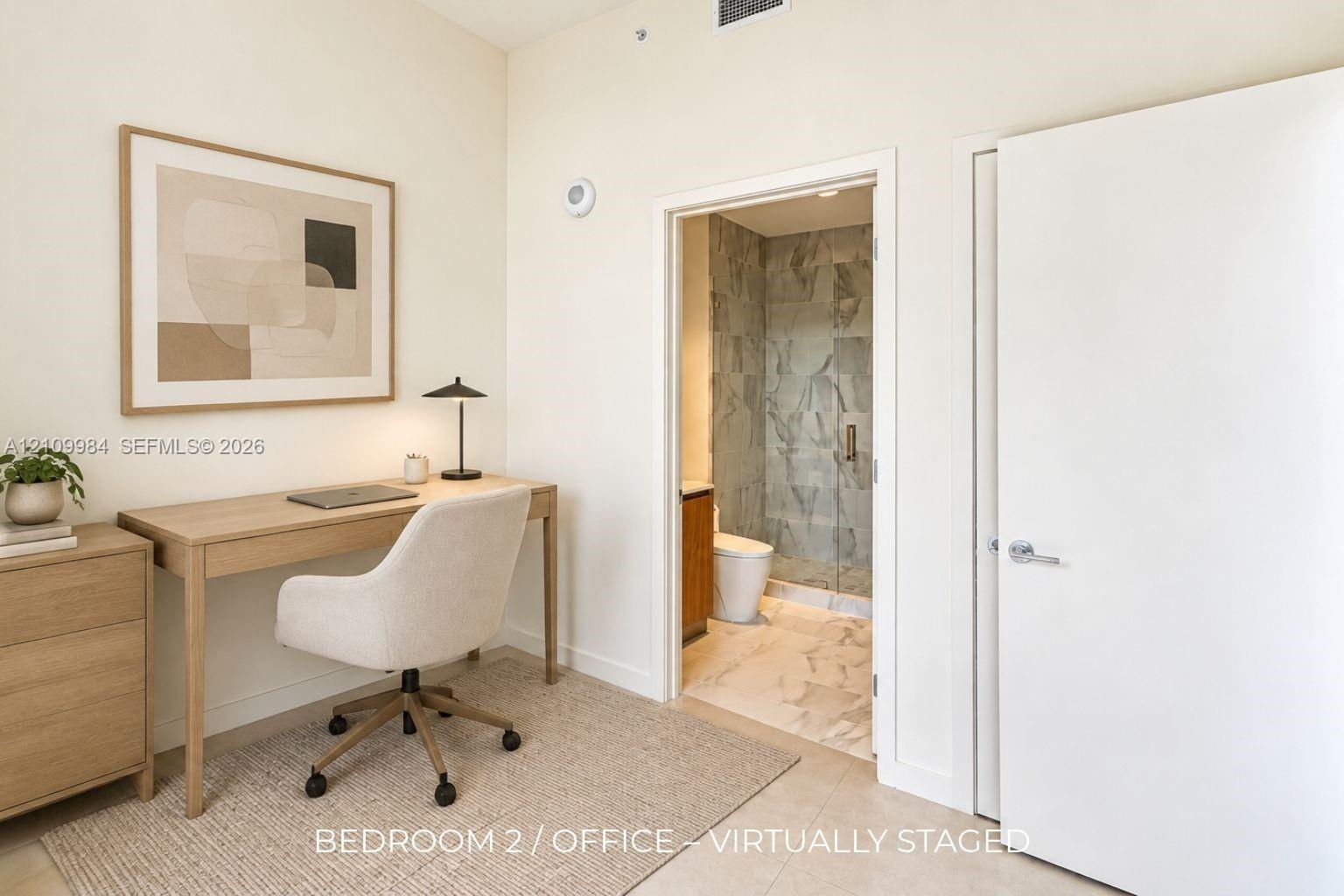 Neutral wall finishes with a full-height doorway opening to a bathroom featuring stone-patterned tile flooring, a glass-enclosed shower with large-for
