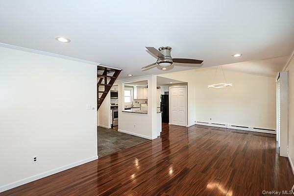 Unfurnished living room featuring dark wood-style floors, a baseboard heating unit, recessed lighting, a ceiling fan, and ornamental molding