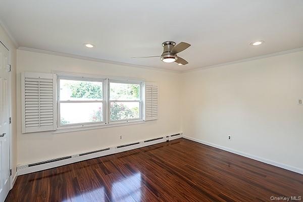 Spare room with a baseboard radiator, dark wood-style flooring, crown molding, a ceiling fan, and recessed lighting
