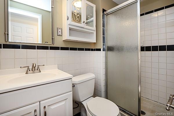 Full bathroom featuring a shower stall, vanity, and tile walls