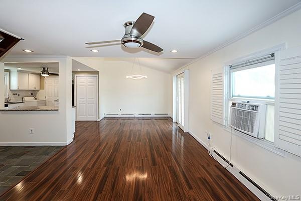 Unfurnished living room featuring a baseboard radiator, dark wood-type flooring, a ceiling fan, recessed lighting, and vaulted ceiling