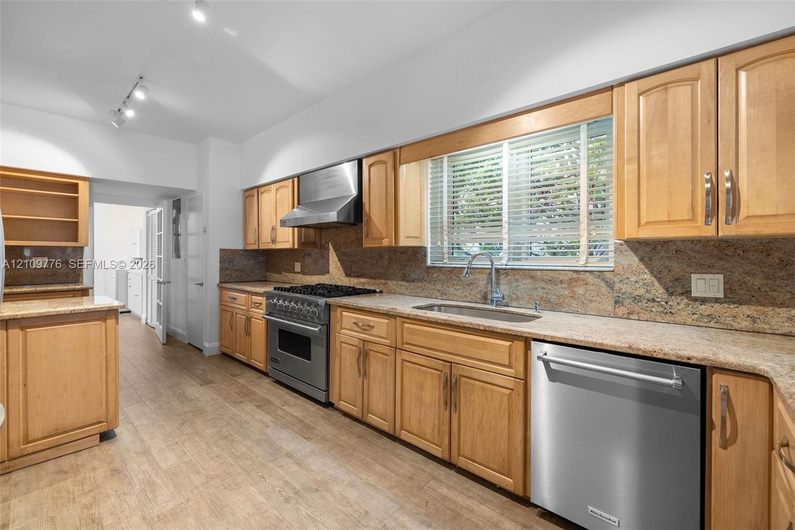 Kitchen featuring natural wood cabinetry, stone countertops, stainless steel appliances, wood-finish flooring, and recessed track lighting