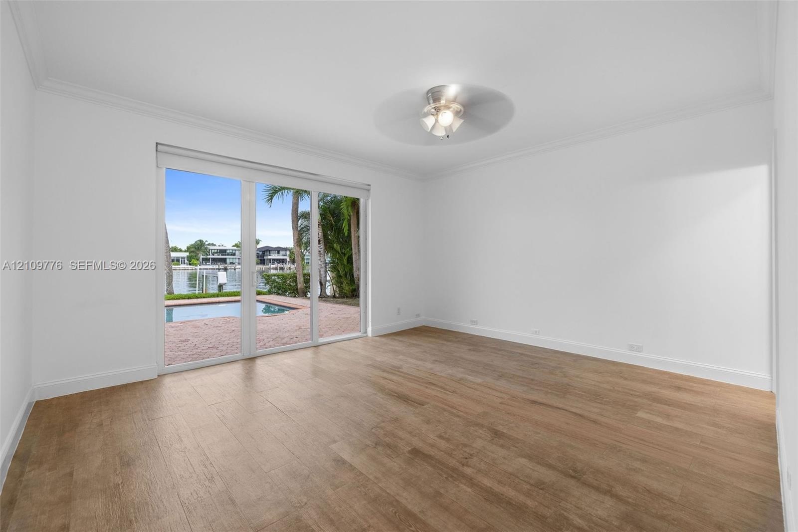 Wood-finish flooring, ceiling fan, and sliding glass doors featuring exterior pool and water access
