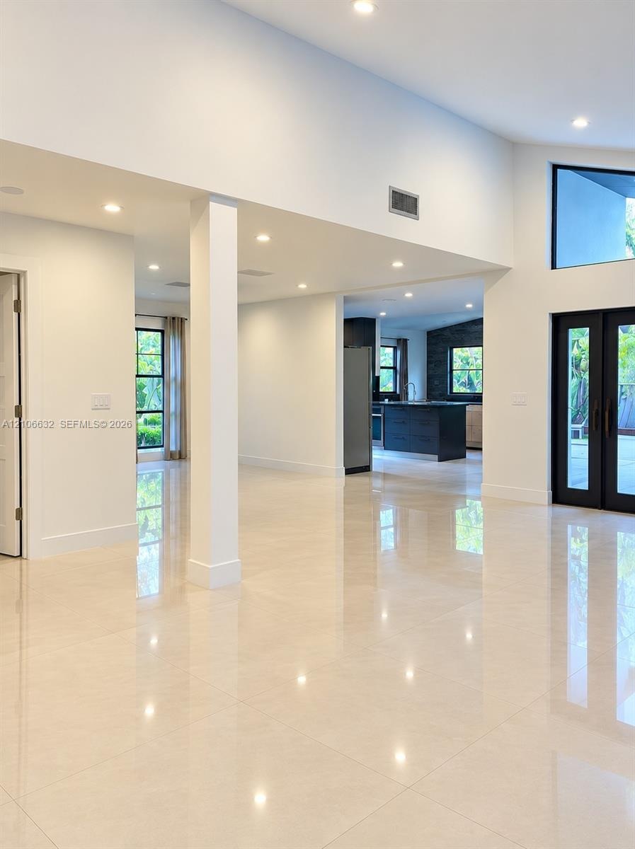 Open interior featuring large-format tile flooring, vaulted ceilings, recessed lighting, access to the garden & terrace.